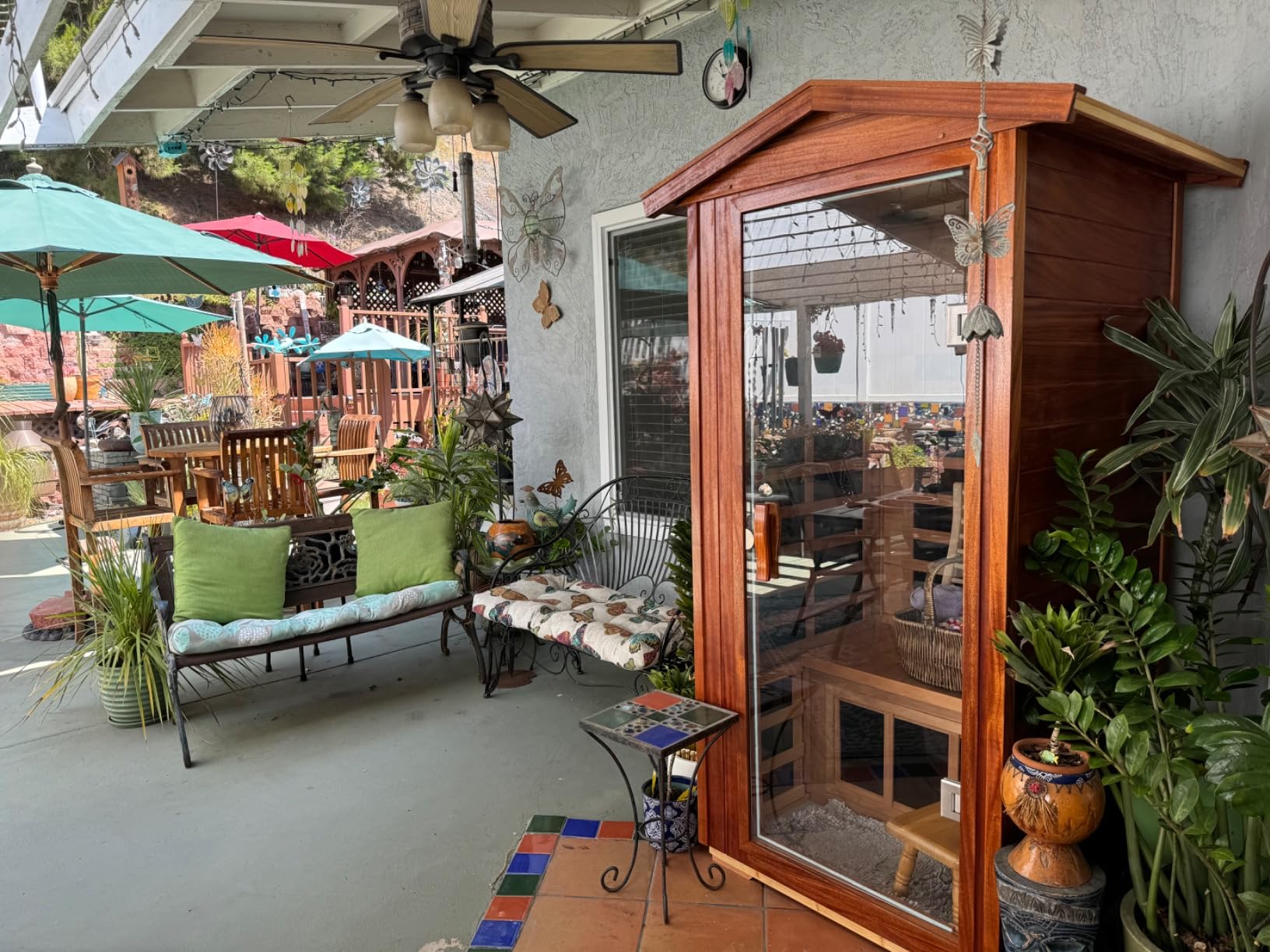 Cedar-toned LTCCDSS outdoor sauna on a covered patio surrounded by plants and patio furniture