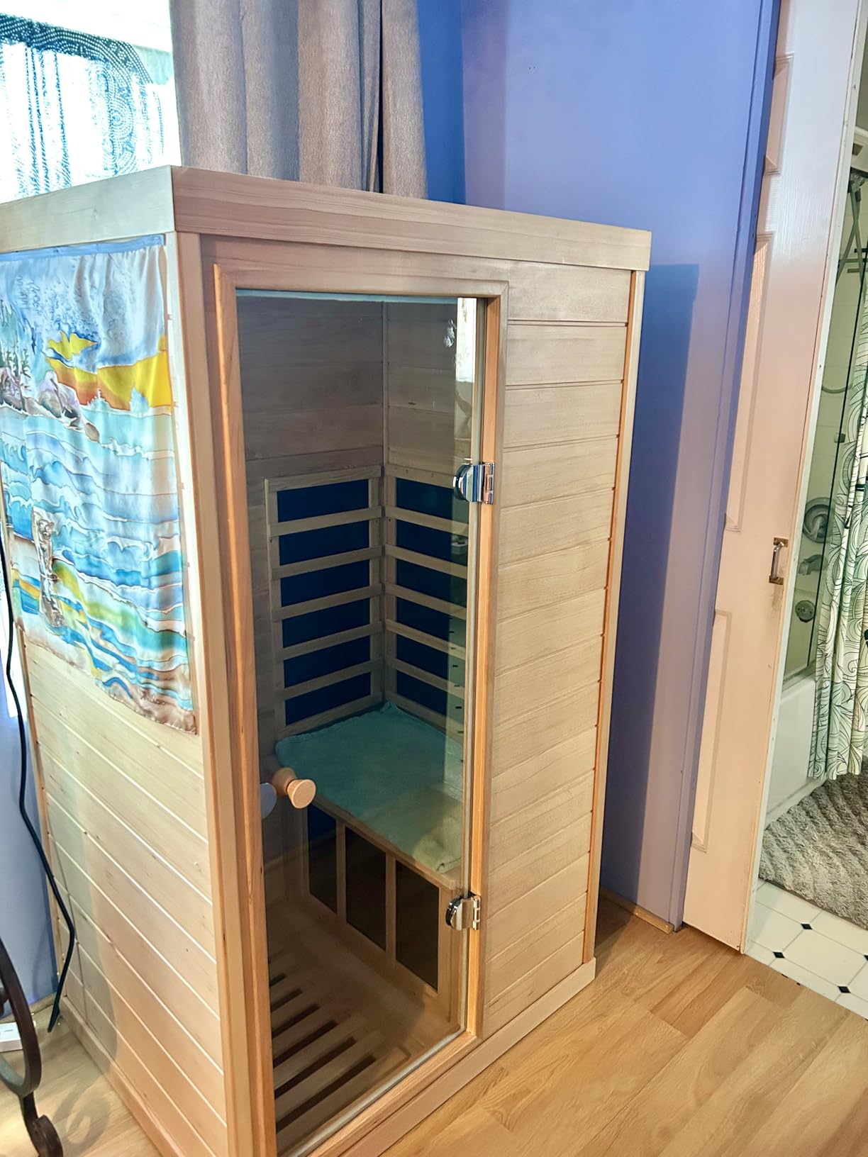 Compact one-person LTCCDSS sauna in a home with a beach painting on the side window