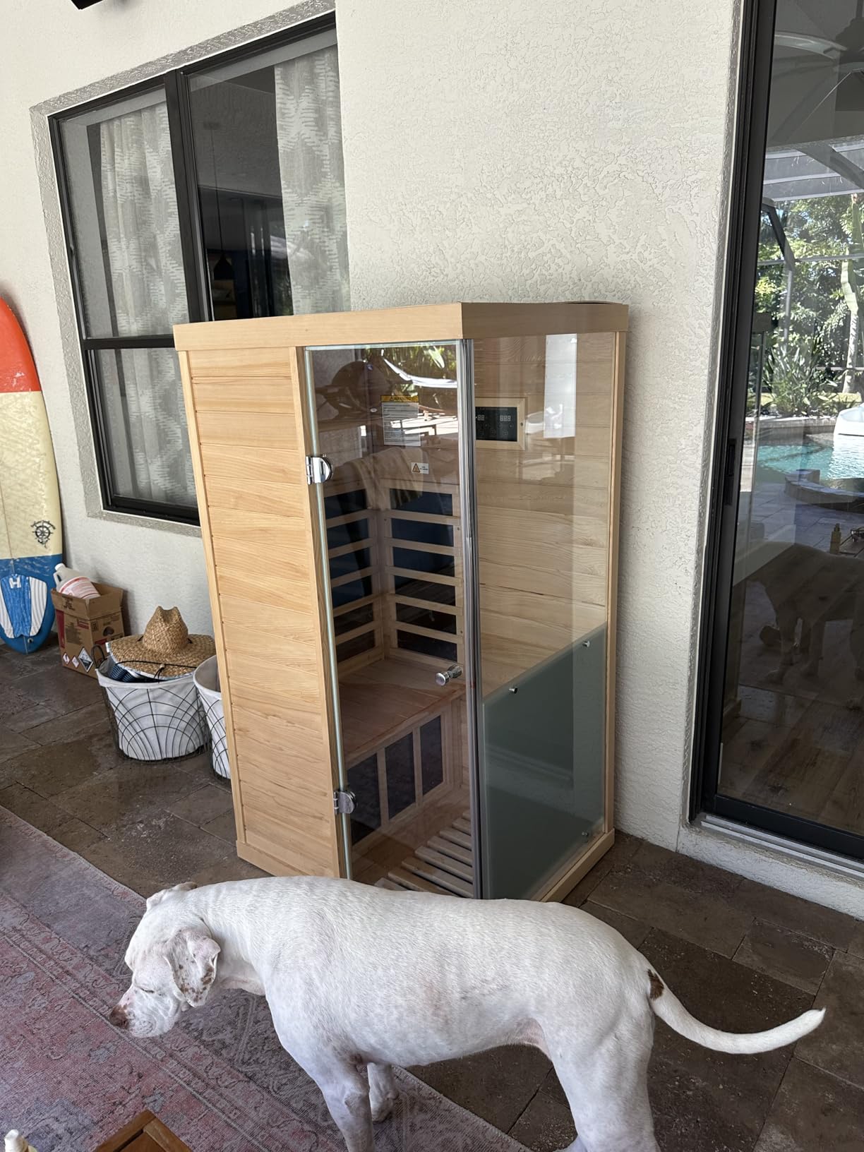 Compact LTCCDSS sauna on a covered patio with the owner’s white dog in front