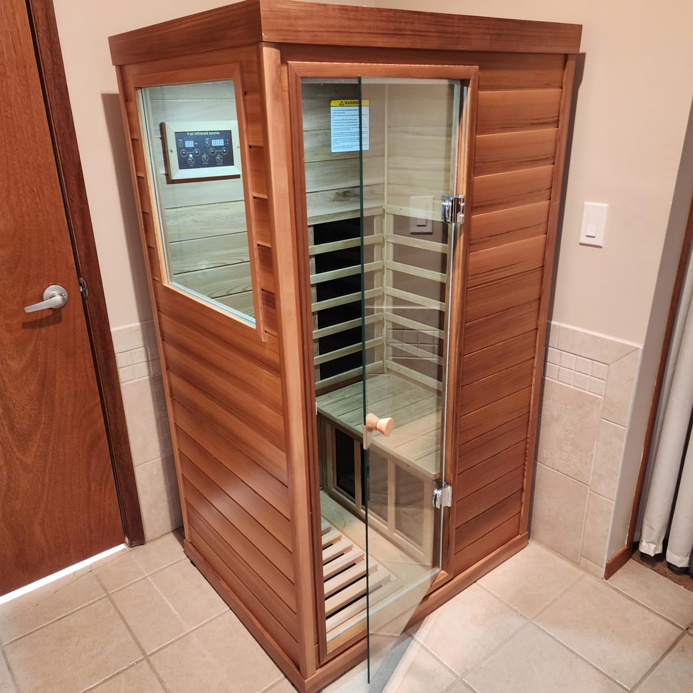 One-person cedar LTCCDSS sauna fitted into the corner of a tiled room